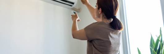 Woman turning on air conditioner.